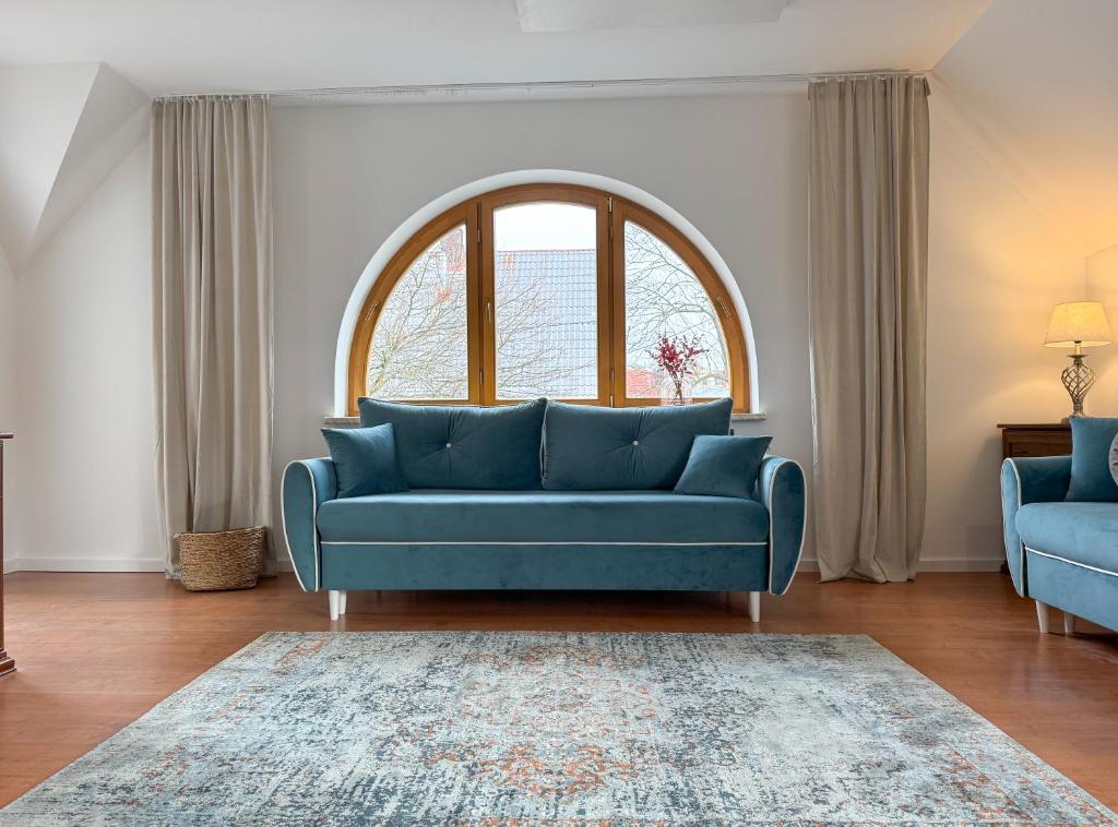 a blue couch in a living room with a window at PARKOVA APARTAMENTY - termy, centrum, park in Jelenia Góra