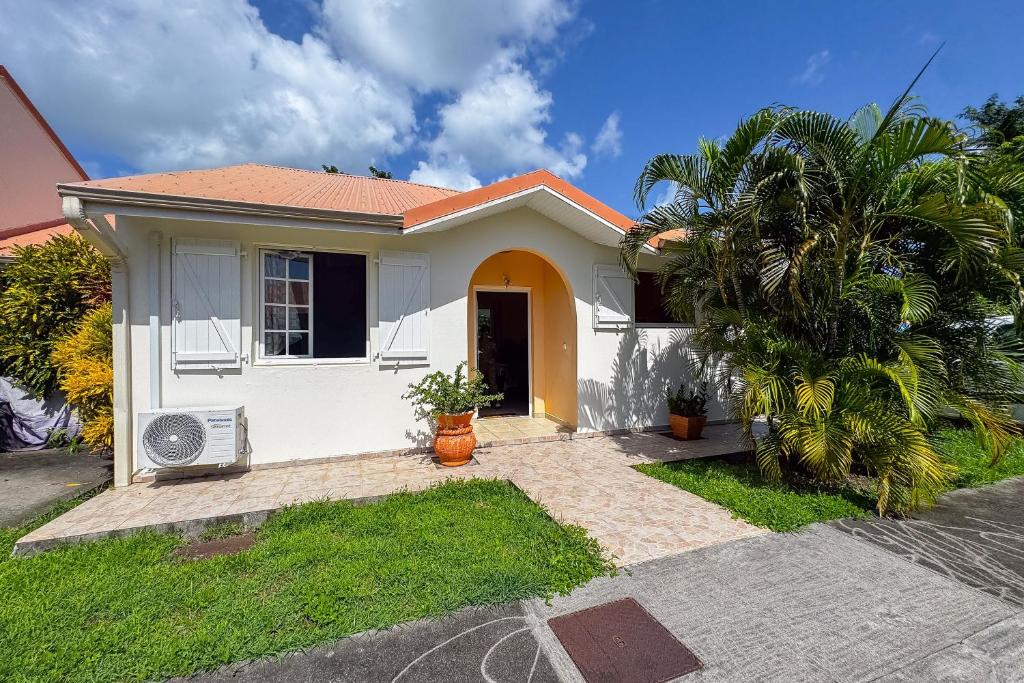 a white house with a palm tree in front of it at Le Cocon Tropical - A 15min à pied de la plage in Sainte-Anne