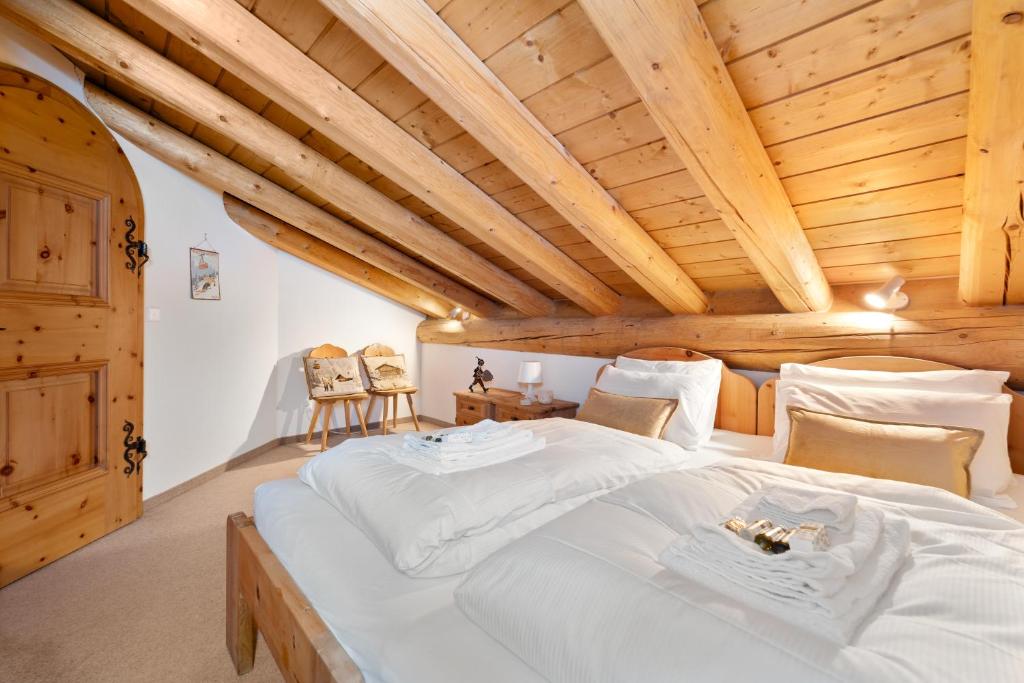 1 dormitorio con 1 cama blanca grande y techos de madera en Chalet St Moritz, en Madulain