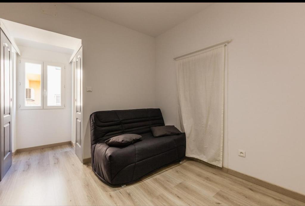 un salon avec un canapé noir dans une pièce dans l'établissement joli studio centre ville, à Ajaccio