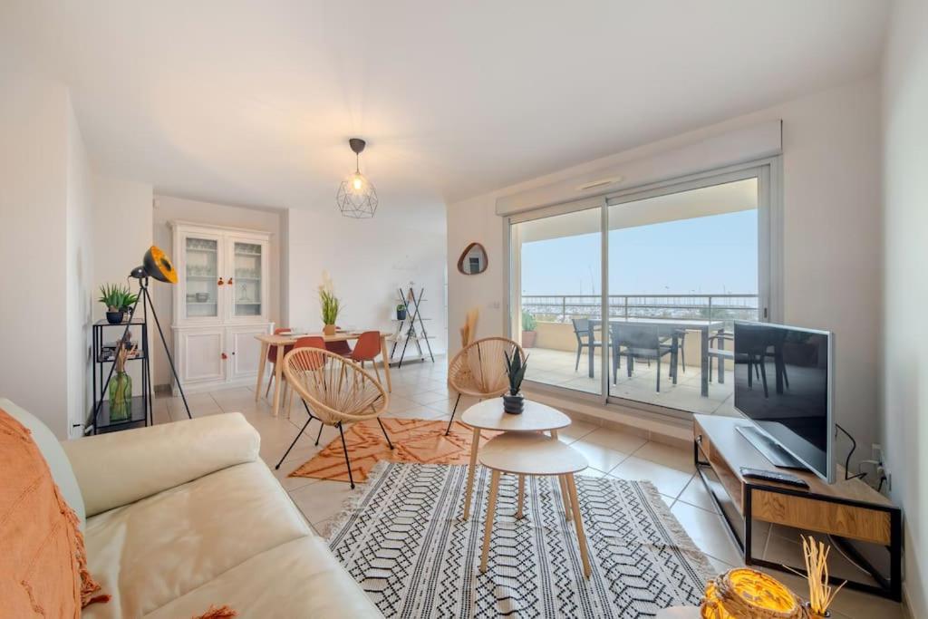 un salon avec un canapé, une télévision et une table dans l'établissement l'Escale du Port - 4 Étoiles - Vue Mer - Parking - Climatisation, à Palavas-les-Flots