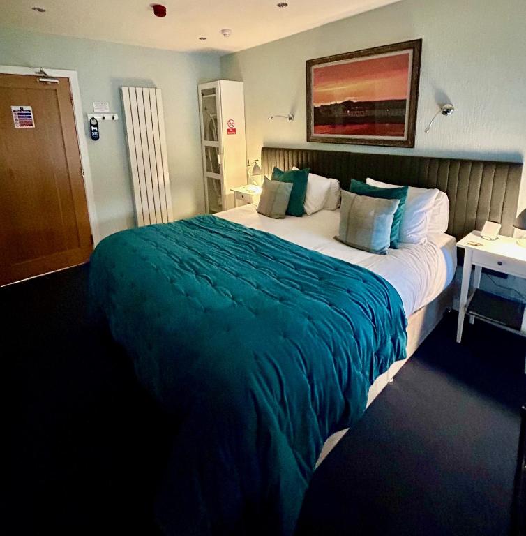 a hotel room with a large bed with green blanket at Lochindaal Hotel in Port Charlotte