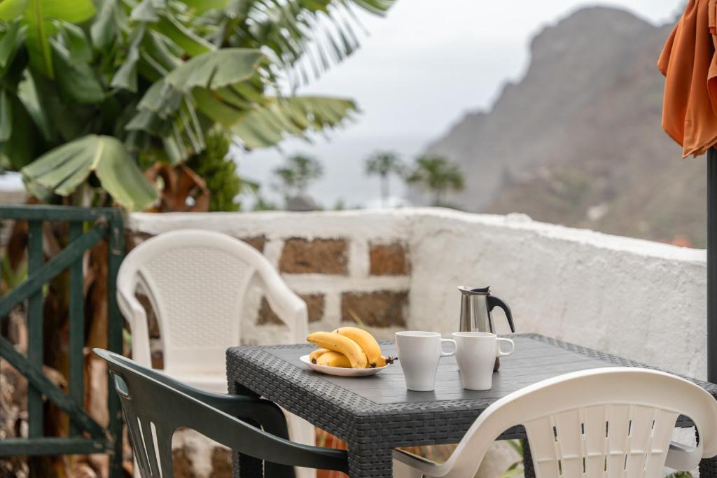 a table with a plate of bananas and cups on it at Casa Rural La Cuadra in Hermigua