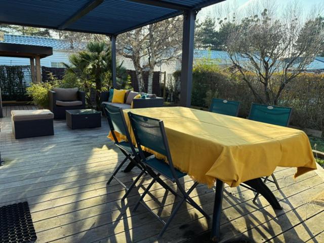 une table et des chaises jaunes assises sur une terrasse dans l'établissement Mobil home dans Parc Résidentiel de Loisirs, à Hauteville-sur-Mer