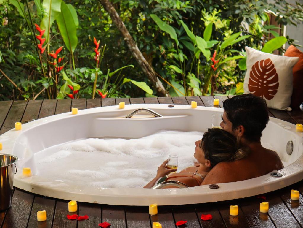 a couple sitting in a bathtub with a glass of wine at Chalés Pura Vida in Itacaré