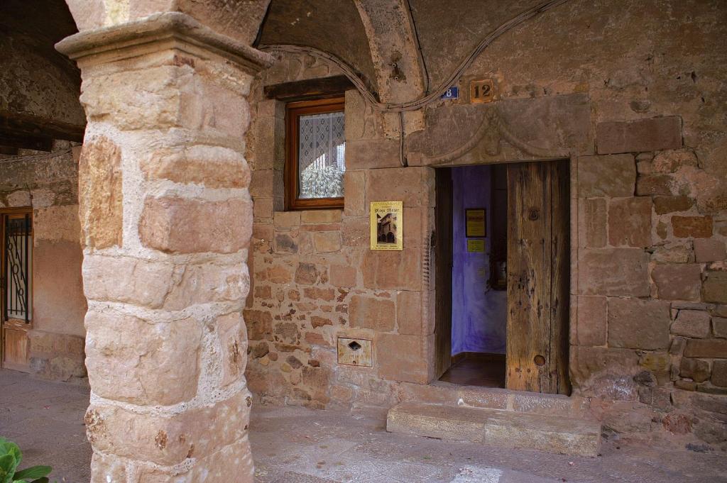 a stone building with a wooden door in it at Allotjaments Plaça Major-Boix in Santa Pau