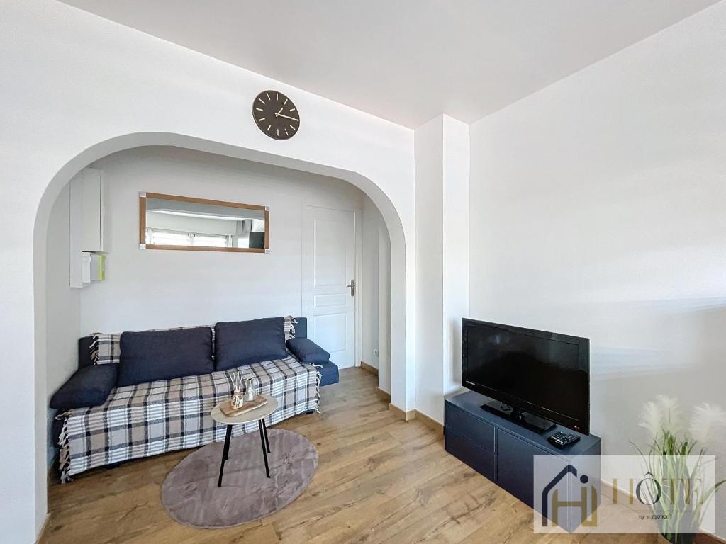 a living room with a couch and a tv at L'Atelier Zen - Confort & Cosy in Dunkerque
