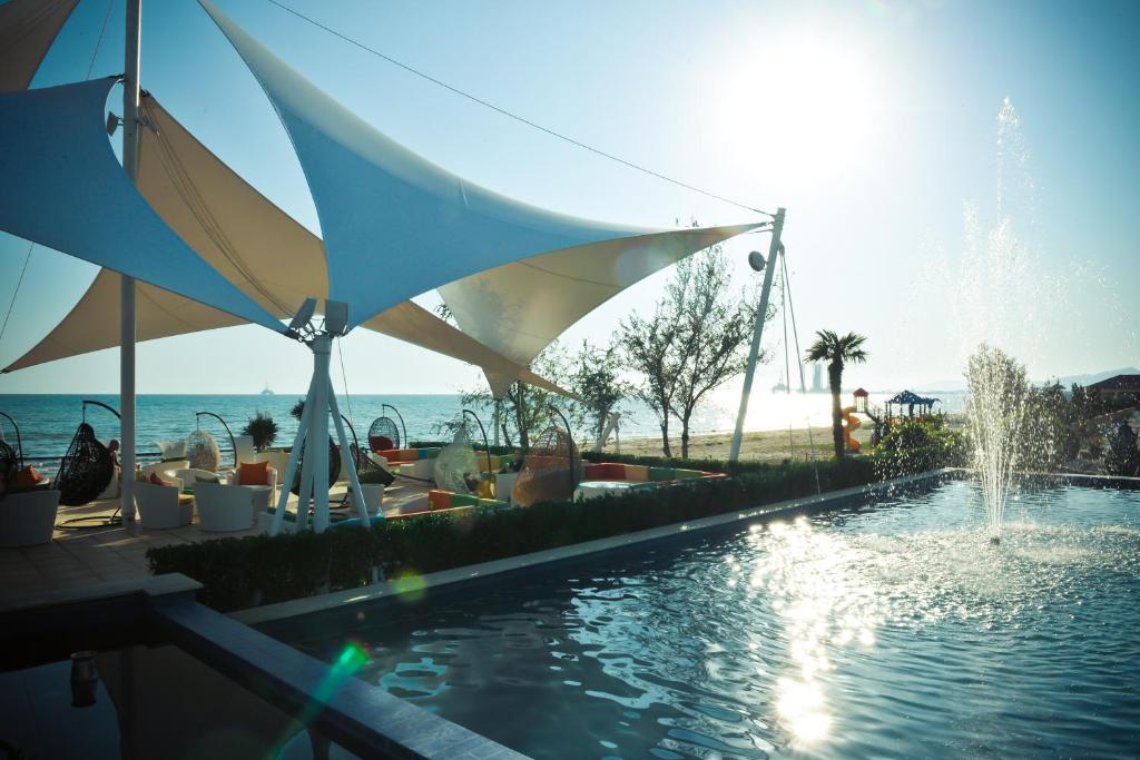 a swimming pool with a fountain and umbrellas at The Crescent Beach Hotel in Baku