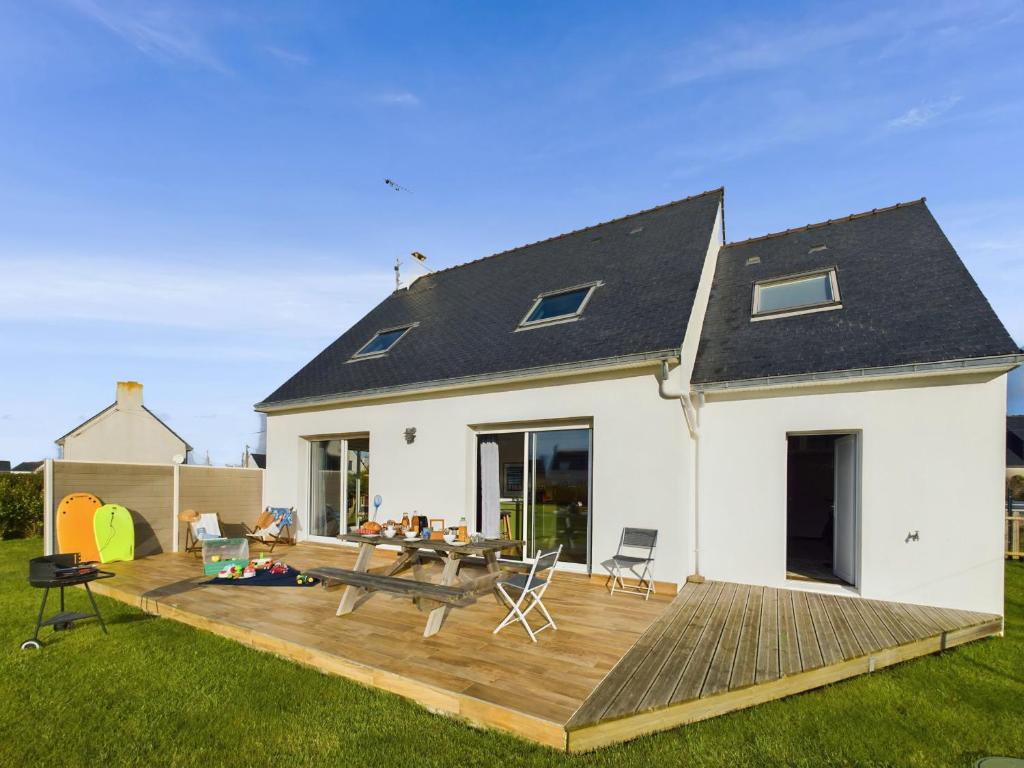 une maison blanche avec une terrasse en bois dans la cour dans l'établissement À 300m de la côte sauvage, maison familiale pour 8, à Penmarcʼh