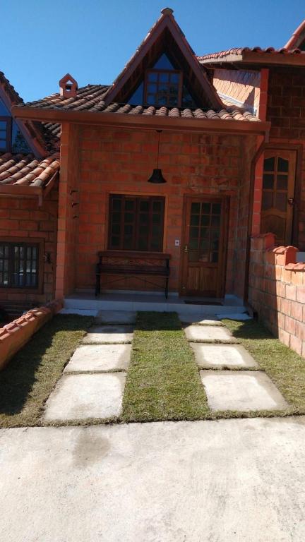 a brick house with a bench in front of it at Chalé Quiririm in Santo Antônio do Pinhal