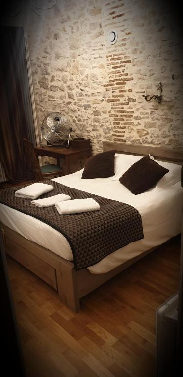 - une chambre dotée d'un grand lit avec des draps blancs et des oreillers noirs dans l'établissement L'écu, à Saint-Amand-Montrond