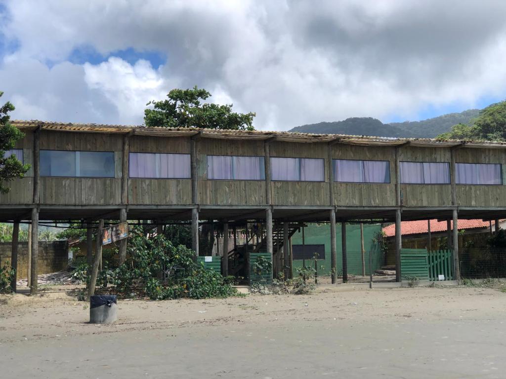 un edificio con techo de madera y un banco en la parte delantera en Pousada Pé Na Areia 1, en Peruíbe