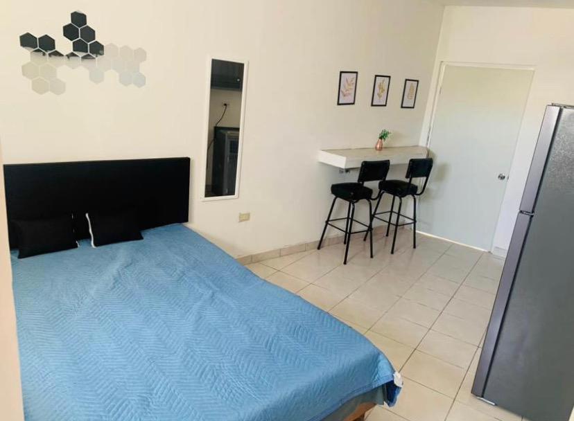 een slaapkamer met een blauw bed en een keuken bij Apartamento Las Aldabas in Chihuahua