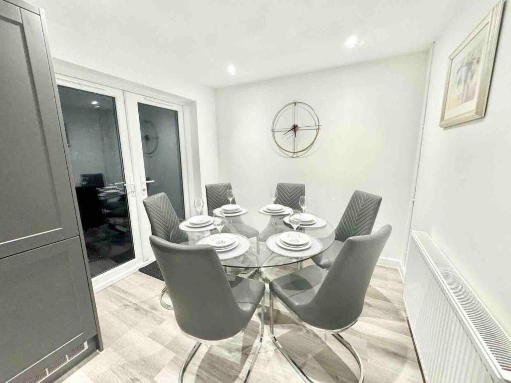 a dining room with a table and chairs and a clock at Swindon 3 bedroom relaxing home with parking - good location for family or contractors in Swindon