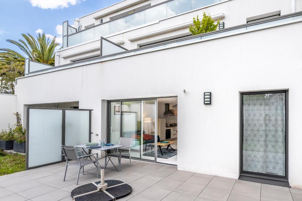 a white house with a patio with a table and chairs at Canon proche de la gare maritime au rdc in Vannes
