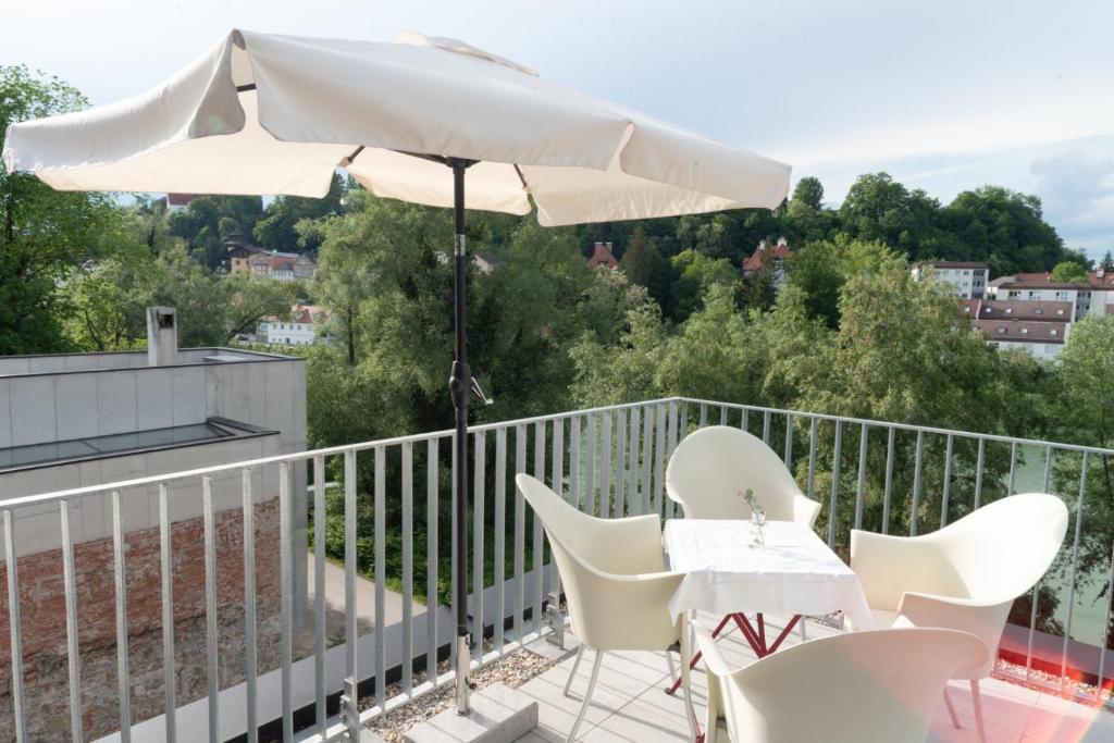 a table and chairs on a balcony with an umbrella at Flösserhaus Steyr - Wohnen am Fluss in Steyr