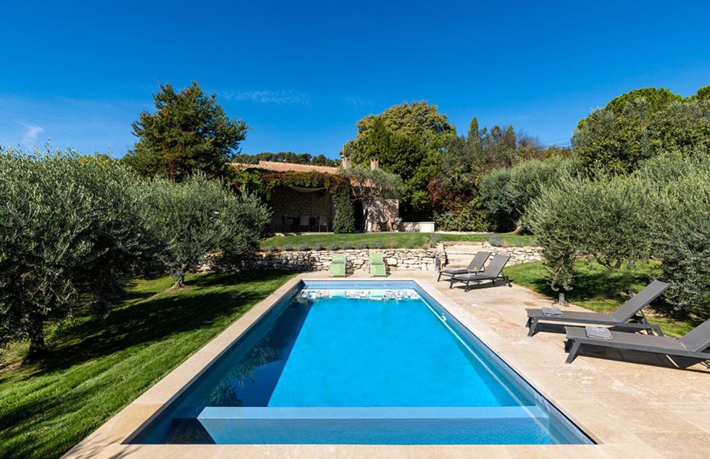 - une piscine dans une cour avec des arbres et une maison dans l'établissement Les Oliviers, à Gordes