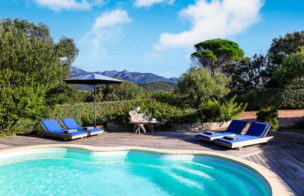 une personne assise à une table à côté d'une piscine dans l'établissement Villa Amelie, à Figari