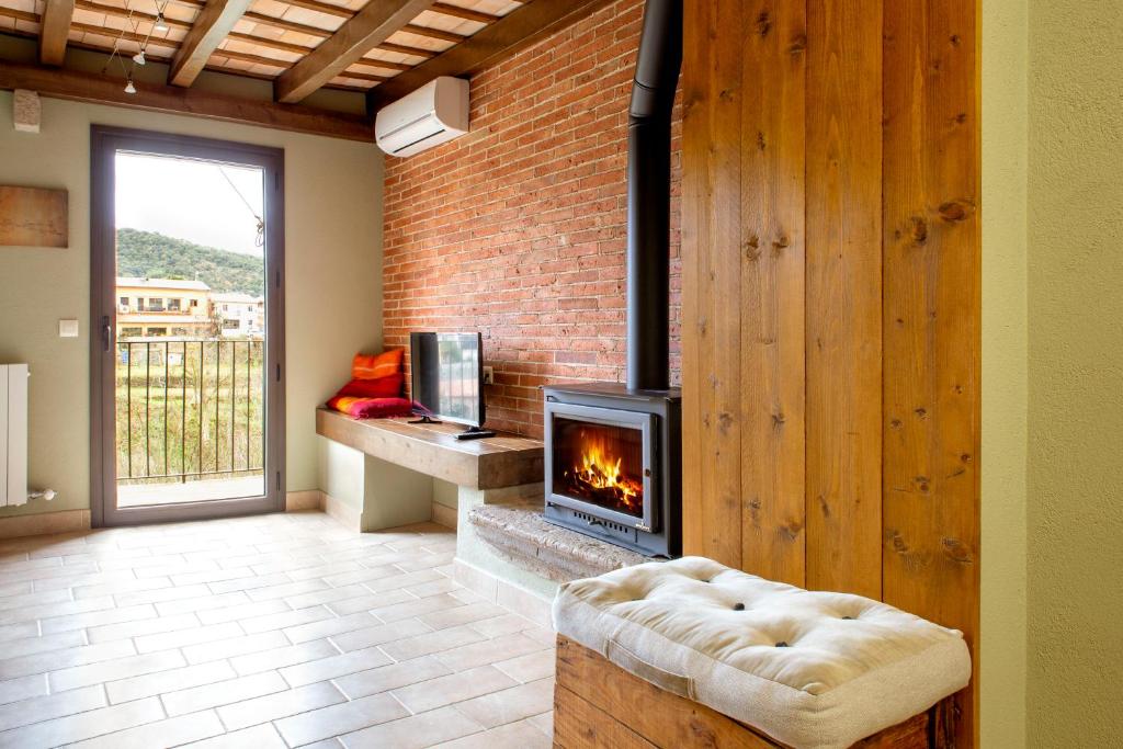 a fireplace in a living room with a brick wall at Allotjaments Plaça Major-Roure in Santa Pau