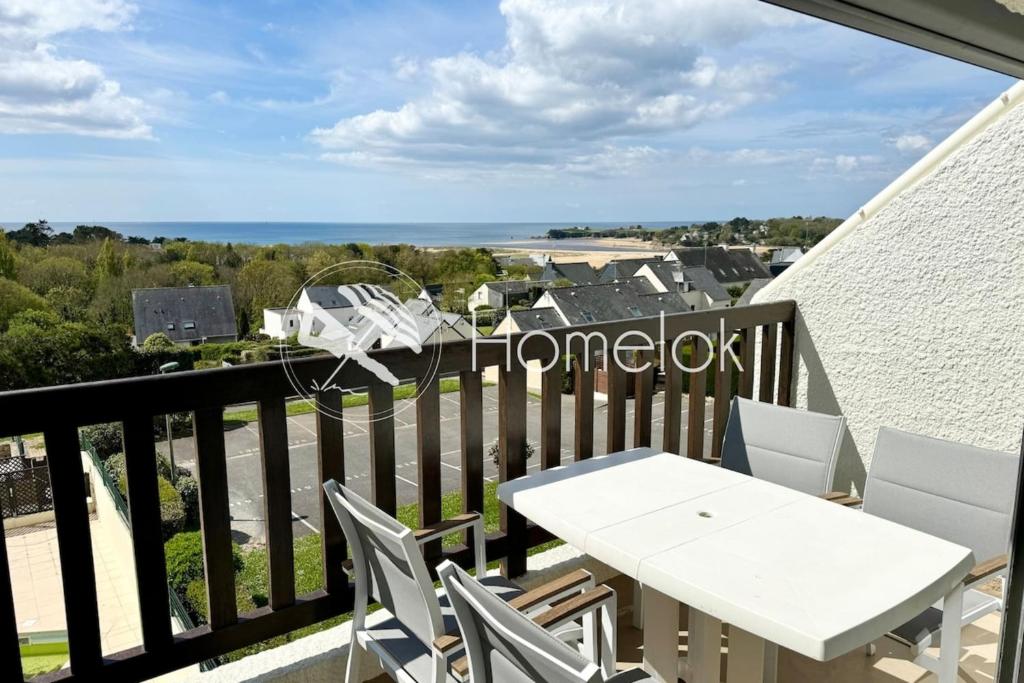 een balkon met een witte tafel en stoelen en de oceaan bij Superbe appartement duplex - Vue mer - Piscine in Guidel