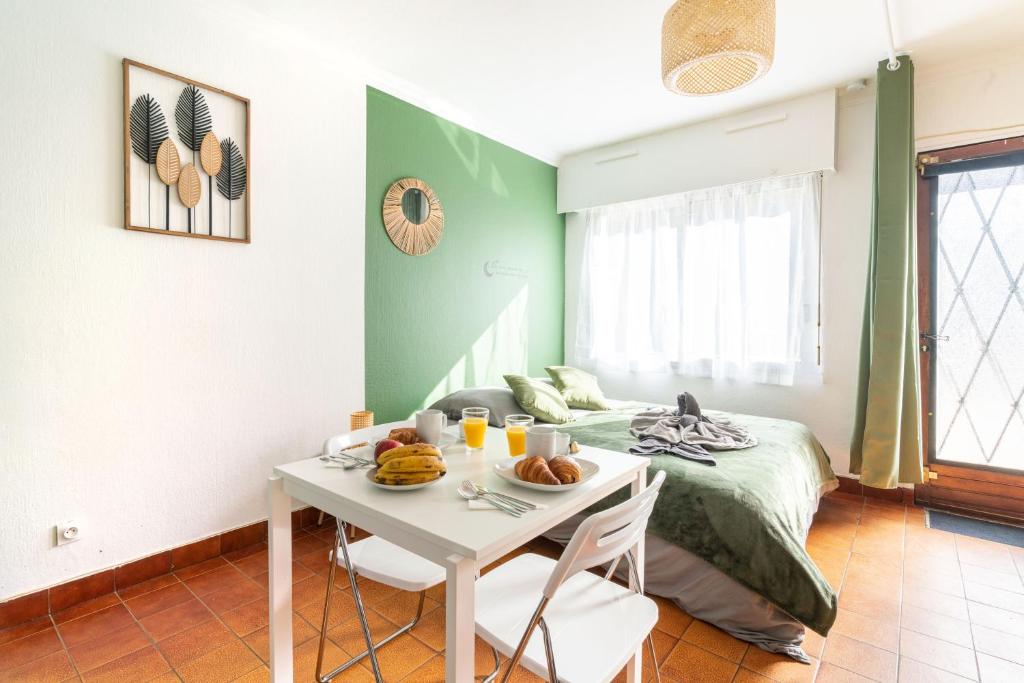 a room with a bed and a table with food on it at Charmant studio avec terrasse, Gare à 200m et parking gratuit in Saint-Cyr-lʼÉcole