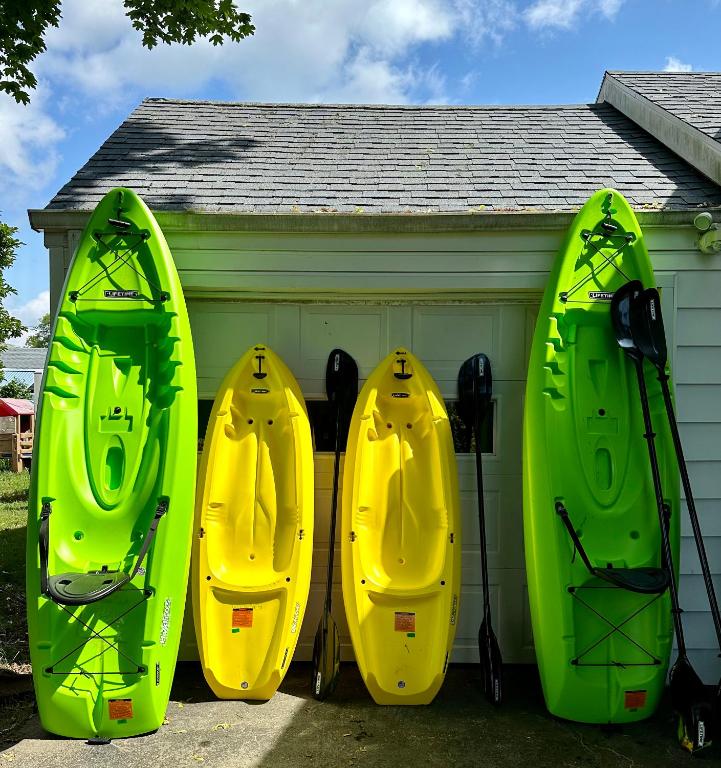 three kayaks are parked next to a garage at Lucky 8 Camp Cozy Coastal Retreat with Hidey Hole & Family Charm in Waterford