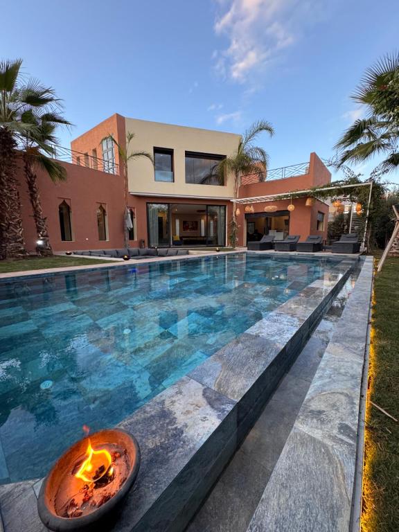 a swimming pool with a fire pit in front of a house at Villa Mattia piscine chauffée sans vis à vis in Marrakech