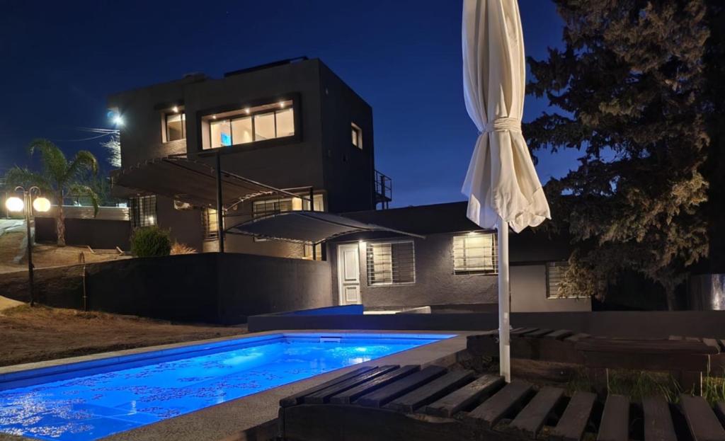 a house with a swimming pool and an umbrella at Quadro Departamentos in Villa Carlos Paz