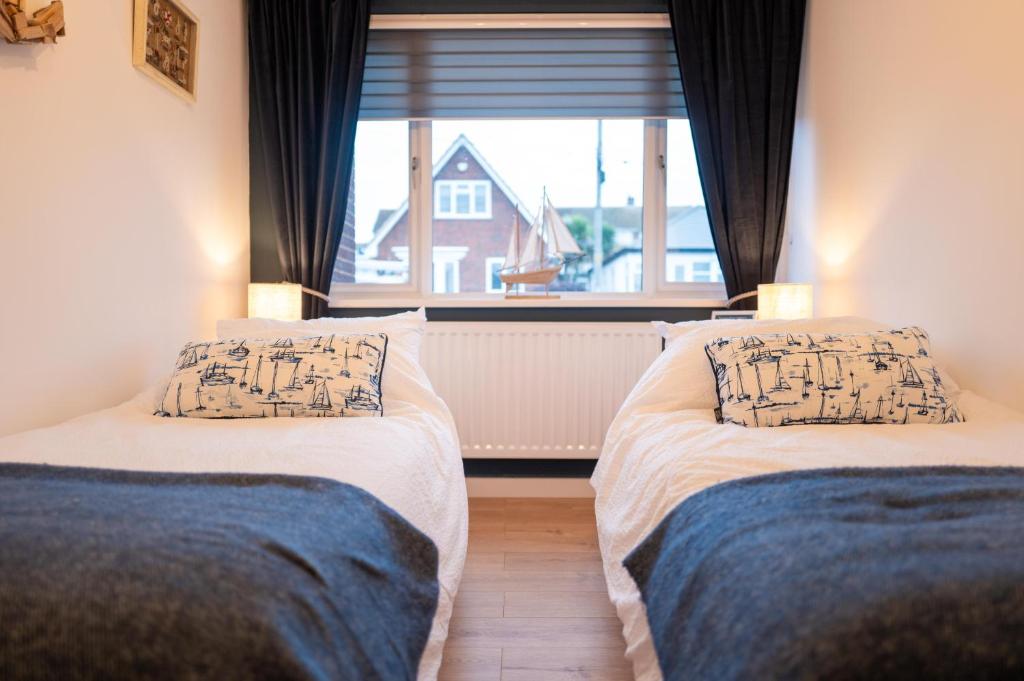two beds in a room with a window at Family & Pet-Friendly Seaside Bungalow with Accessible Features in Minster