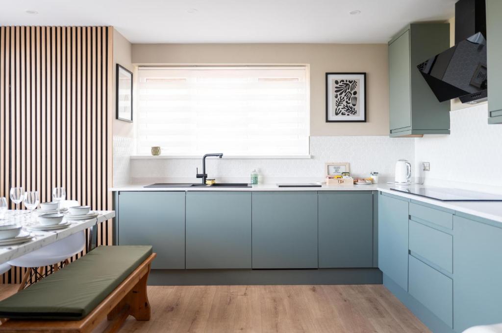 a kitchen with blue cabinets and a table at Family & Pet-Friendly Seaside Bungalow with Accessible Features in Minster