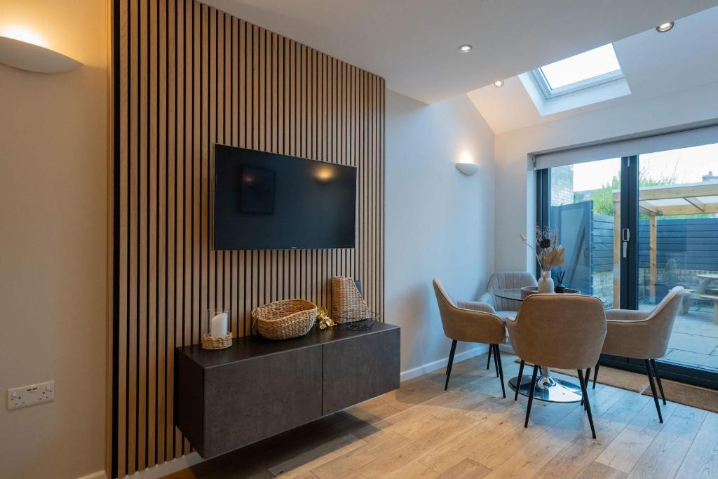 a living room with a table and a television on a wall at Beautiful 2 Bedroom Home in Cambridge