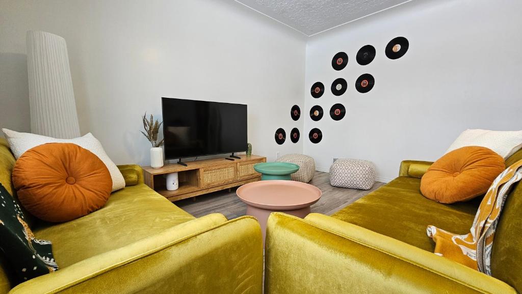 a living room with two yellow couches and a tv at Retro Retreat - 3bdr, 1 bath, close to city center in Edmonton