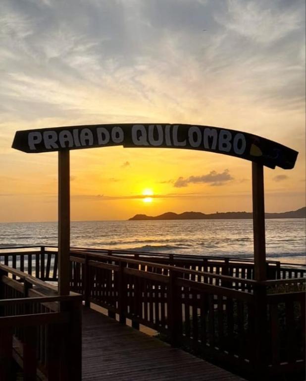 a sign on a pier with the sunset in the background at Apartamento praia do quilombo Centro - 02 in Penha