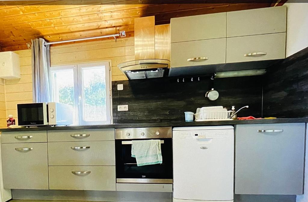 Il comprend une cuisine équipée d'une cuisinière et d'un lave-vaisselle. dans l'établissement Chalet climatisé avec vue lac, à Lissac-sur-Couze