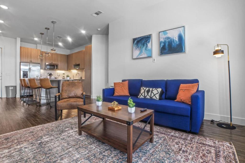 a living room with a blue couch and a table at Luxurious New Unit 2Bd2Ba Pool, Golf Sim in Austin