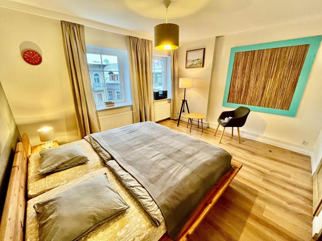 Un dormitorio con una cama grande y una silla. en W parku przy teatrze, en Szczawno-Zdrój