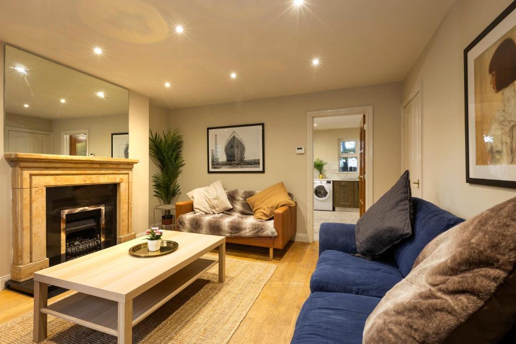 a living room with a blue couch and a fireplace at The Annadale - Luxury 3 bd House - Gold Short Term Stays in Belfast