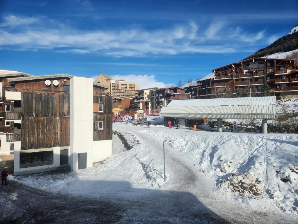une rue enneigée dans une ville avec des bâtiments dans l'établissement Appartement 4 personnes ski aux pieds parking couvert, à Les Deux Alpes