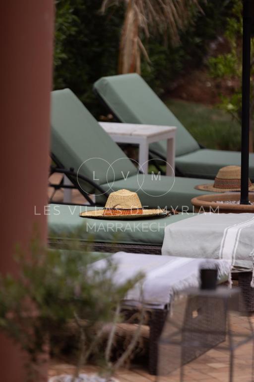 two lounge chairs and hats sitting on a table at Dar Nadim sur le Golf de Samanah in Marrakesh