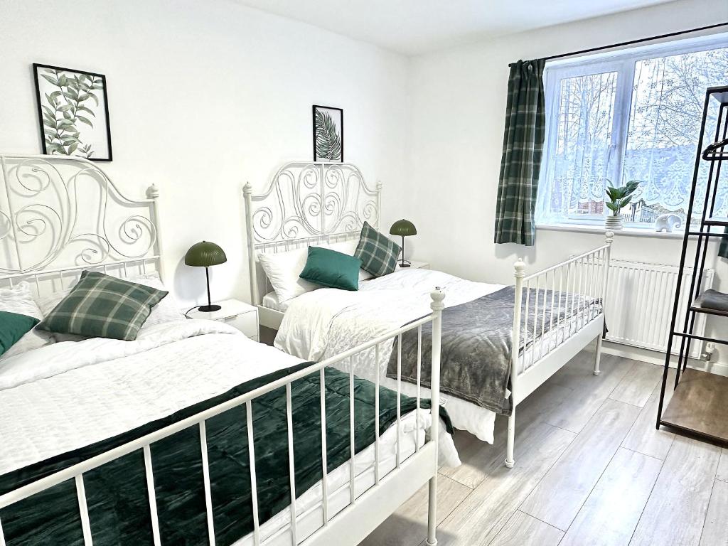 a bedroom with two beds and a window at 4B4B Entire House Sleeps 11 Driveway Parking near Coventry University and City Centre in Coventry