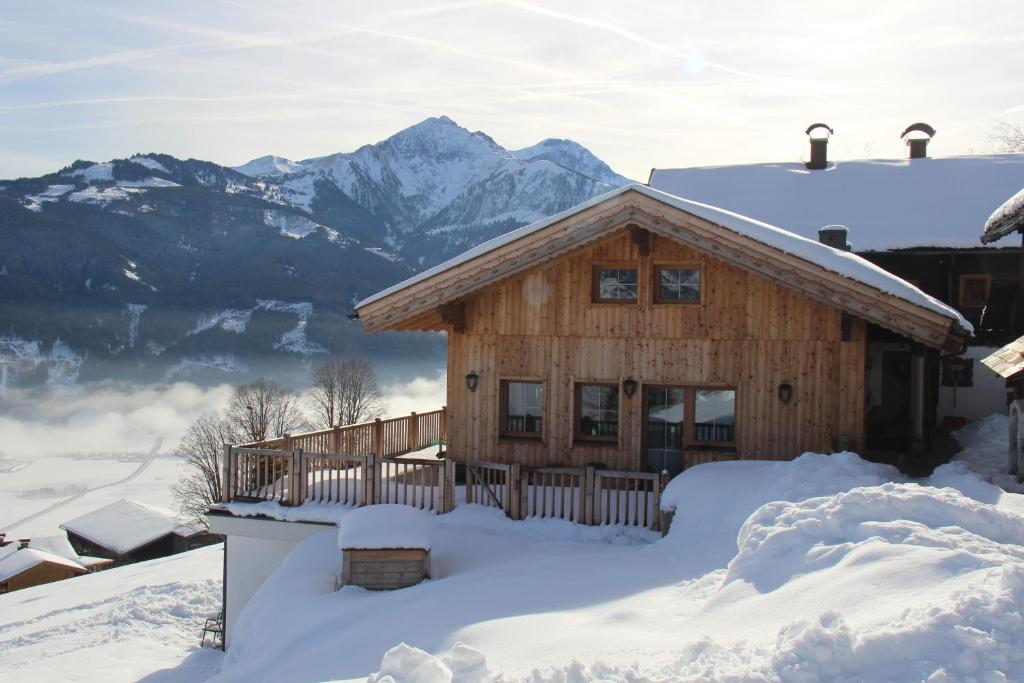 een blokhut in de sneeuw met bergen op de achtergrond bij Ferienwohnung Mitterleithengut in Zell am See
