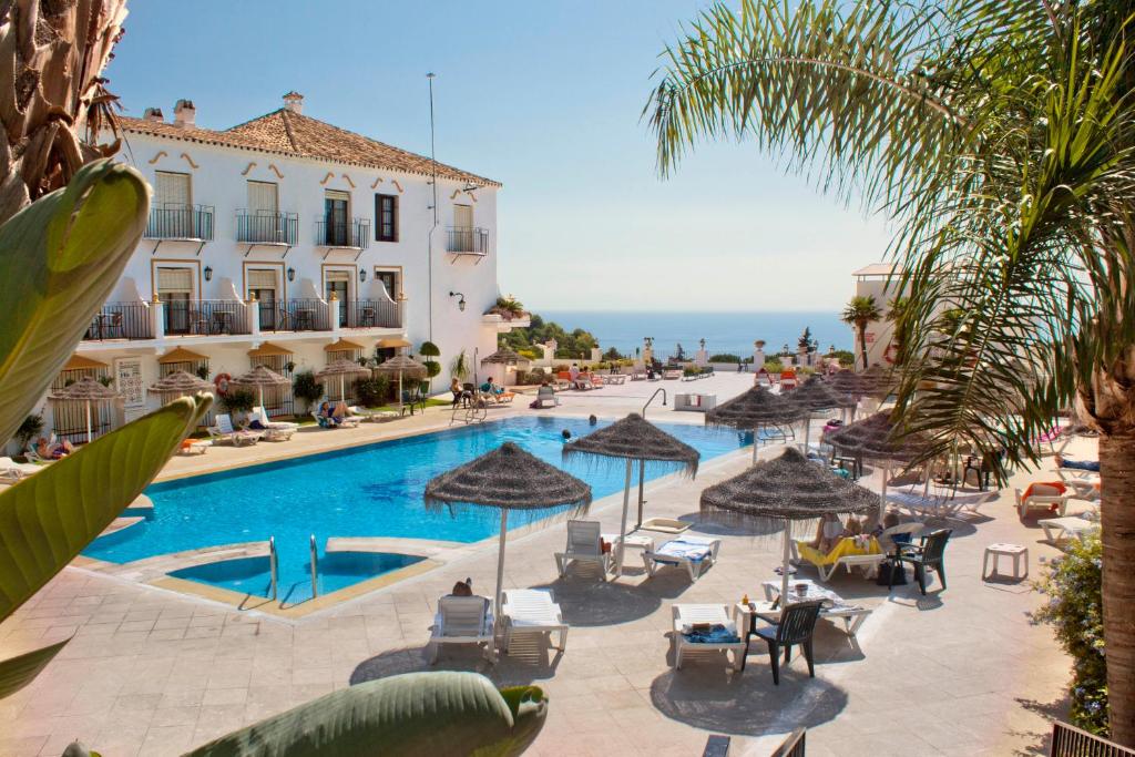 a pool with chairs and umbrellas next to a building at TRH Mijas in Mijas