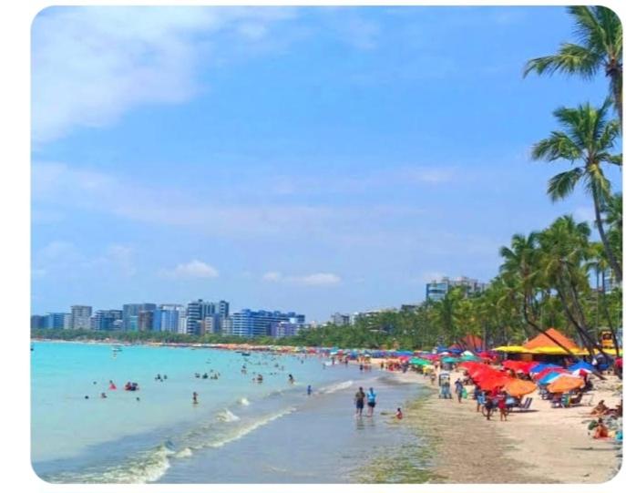 a beach with a bunch of people in the water at Pousada Deus Provera in Maceió