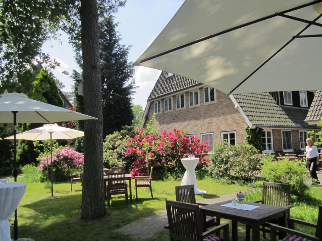un patio avec des tables et des parasols dans une cour dans l'établissement Gasthof Menke, à Niederhaverbeck
