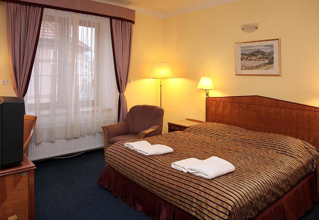 Hotel Prajer في Vodňany: غرفة فندق عليها سرير وفوط