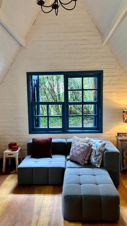 a living room with a couch and a large window at Provence Cottage in Camanducaia
