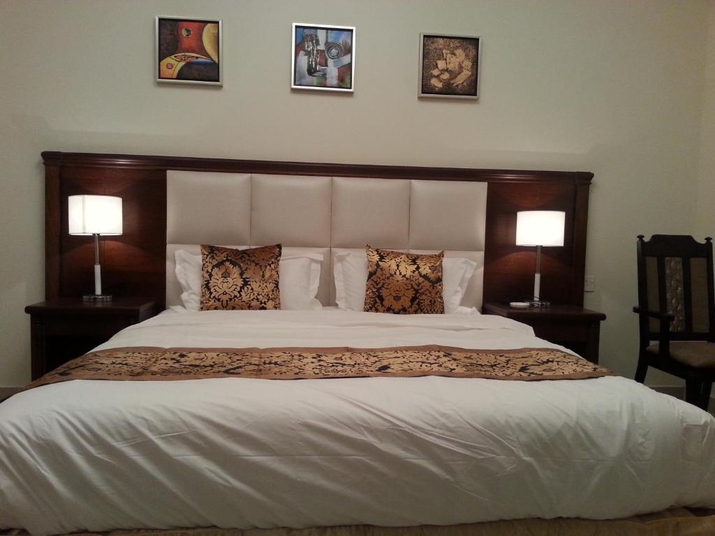 a bedroom with a large bed with two lamps at Lara Al Jawf Hotel Apartments in Sakakah
