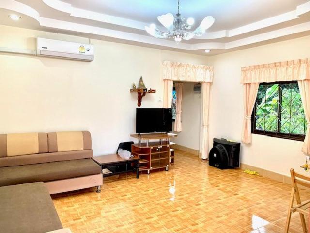 a living room with a couch and a tv at Bangtao15 Private House in Ban Lum Fuang