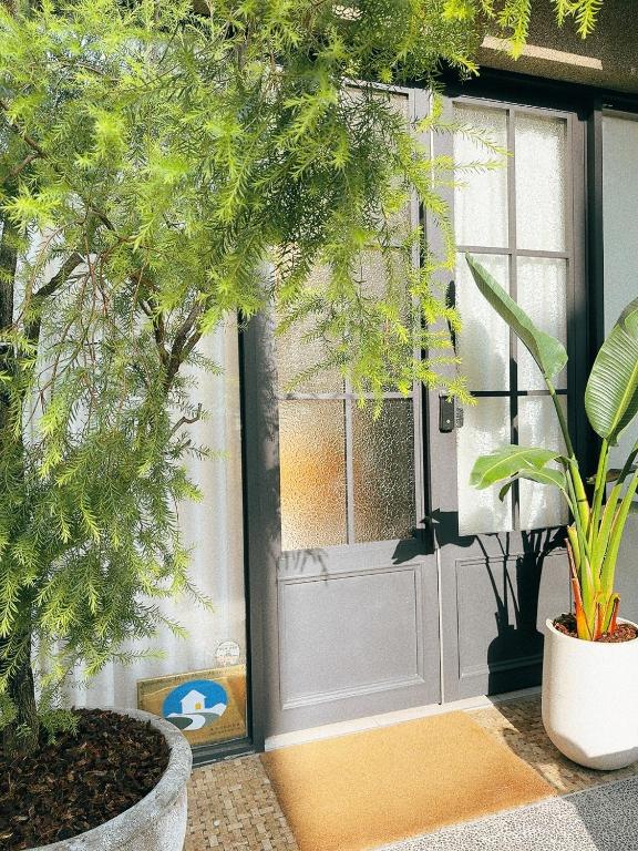 台南梧同包棟民宿La Petite Maison I Entire House BnB I 寵物友善 I 國旅卡 I 出差商旅可報帳 I 電動麻將 I NETFLIX I Nintendo Switch I MOD I一軒家貸切的一座有盆栽植物的房子的前门