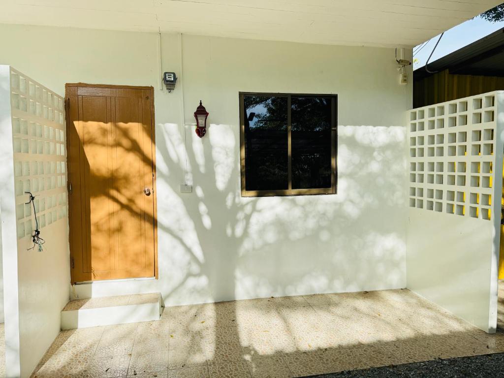 a front door of a house with a shadow on the wall at House Garden บ้านสวนสุพัตรา Room in Bang Lamung